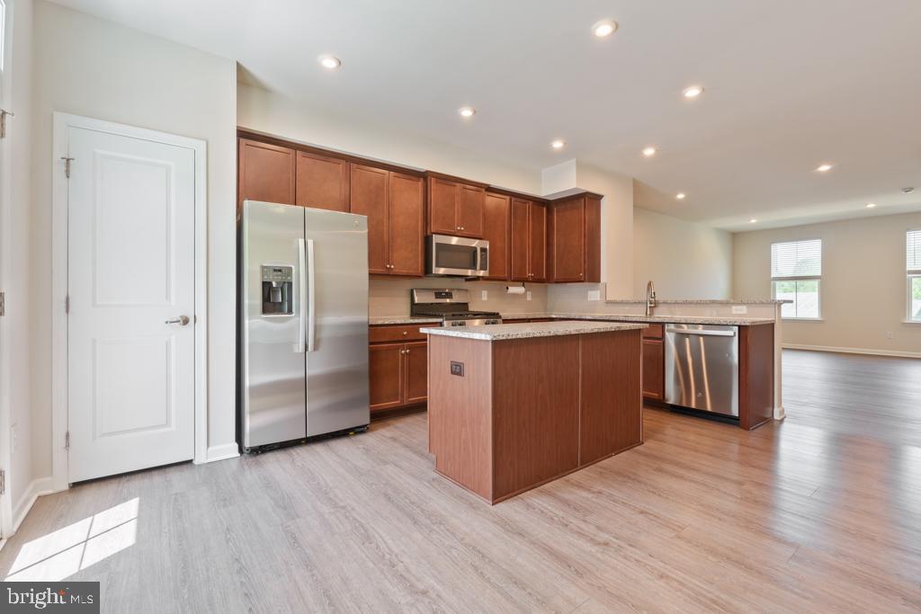 39 Sidney Lane Stratford, NJ 08084 - Photo 6 of 21 a kitchen with stainless steel appliances granite countertop a stove a refrigerator a sink a microwave oven with wooden floor and cabinets