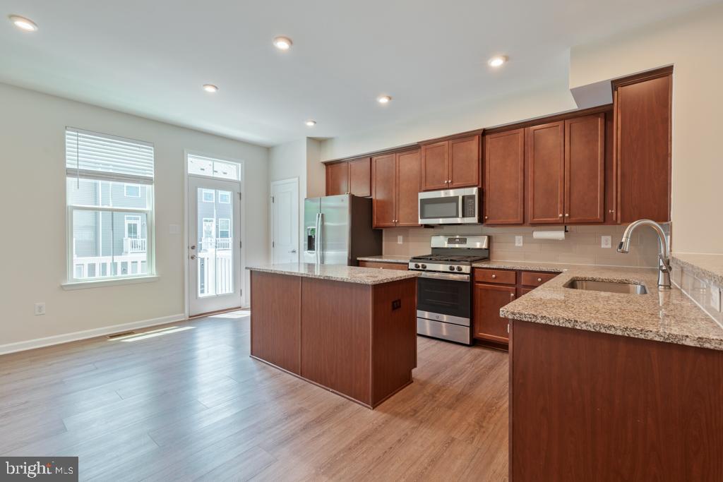 39 Sidney Lane Stratford, NJ 08084 - Photo 7 of 21 a kitchen with granite countertop wooden floors stainless steel appliances a sink and a window