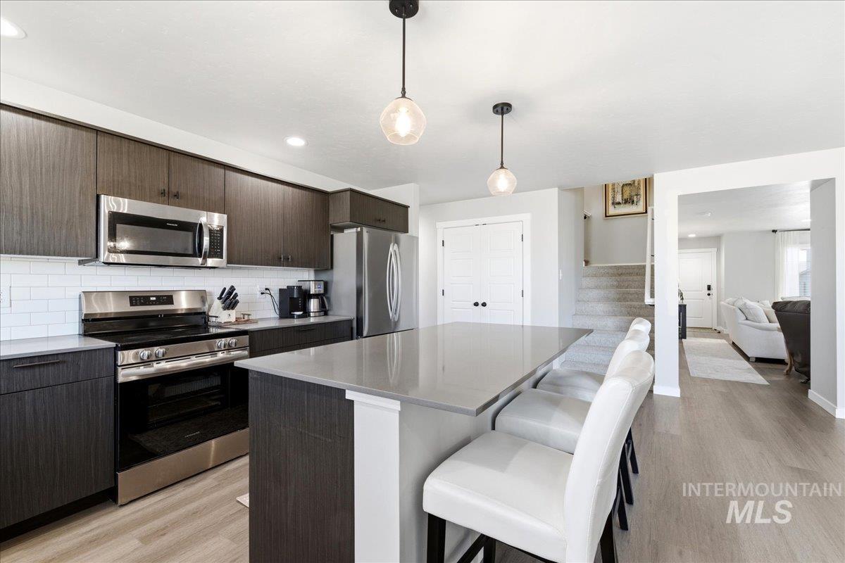 5392 South Memory Way Meridian, ID 83642 - Photo 11 of 39 Kitchen featuring stainless steel appliances, light wood-style flooring, pendant lighting, and a kitchen bar