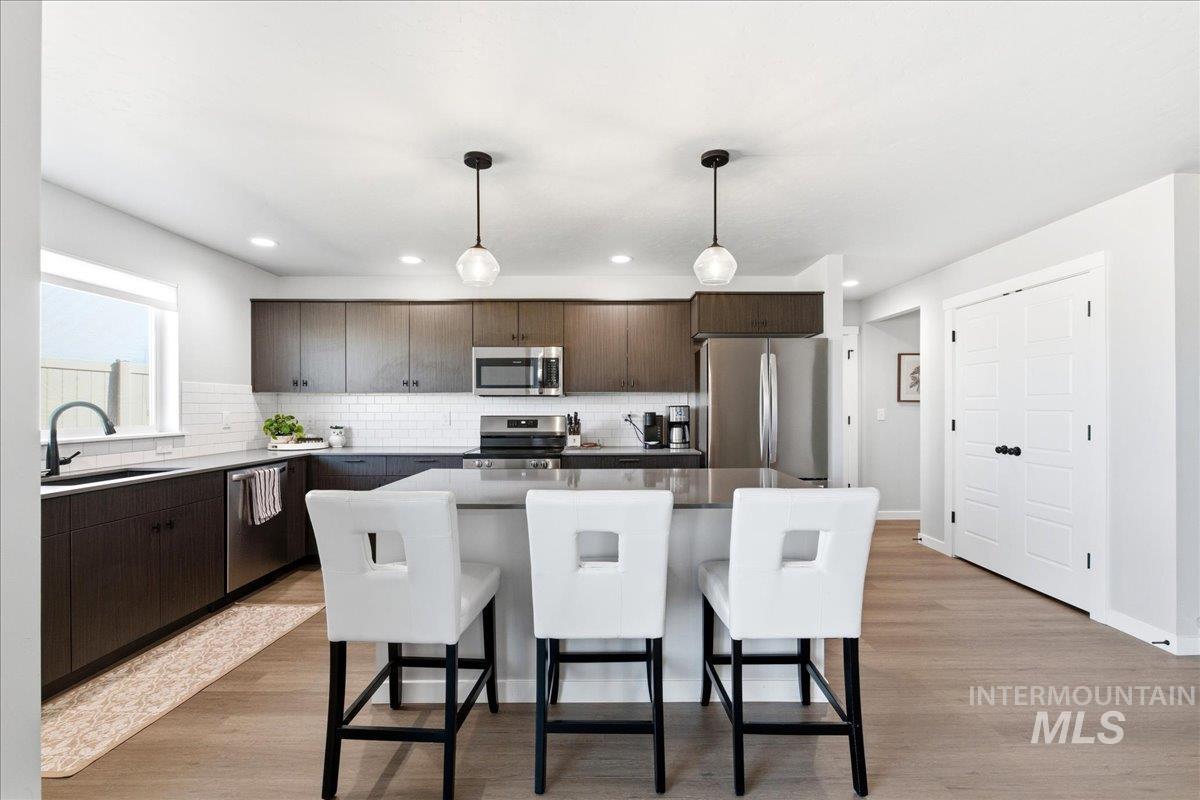 5392 South Memory Way Meridian, ID 83642 - Photo 12 of 39 Kitchen featuring dark wood finish cabinetry, a breakfast bar, a kitchen island, and stainless steel appliances