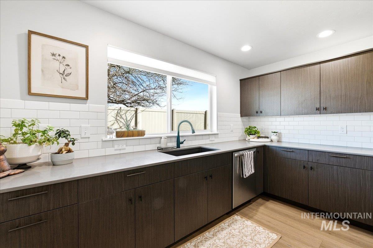 5392 South Memory Way Meridian, ID 83642 - Photo 14 of 39 Kitchen featuring dark wood finish cabinetry, stainless steel dishwasher, light wood finished floors, backsplash, and recessed lighting
