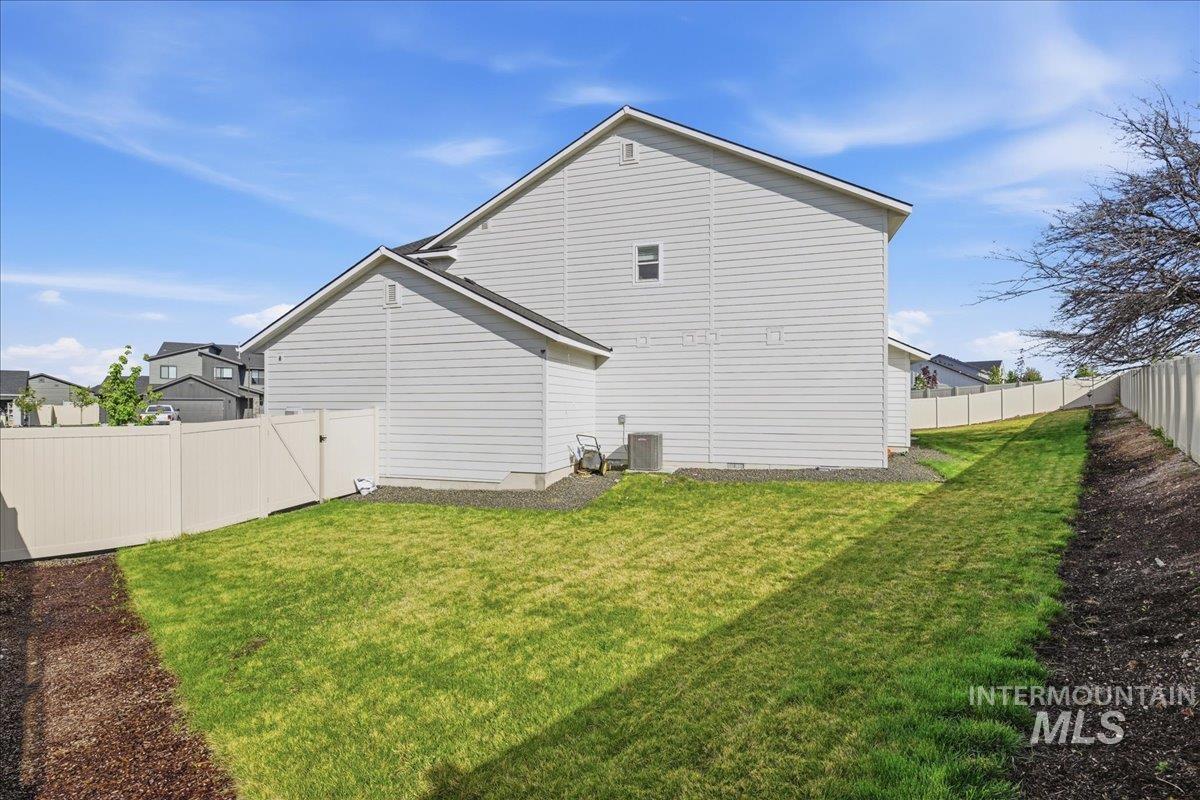 5392 South Memory Way Meridian, ID 83642 - Photo 36 of 39 Expansive side yard featuring a manicured lawn, full privacy fencing, and a gravel perimeter around the home's foundation