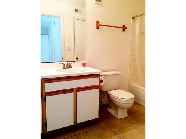 a bathroom with a granite countertop sink a toilet and shower