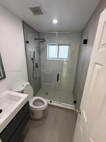 a bathroom with a granite countertop sink a toilet and shower