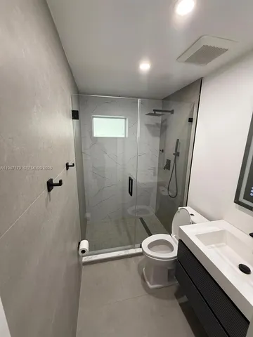 a bathroom with a granite countertop sink toilet and shower