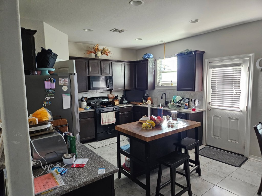 5710 Micah Lane Rosenberg, TX 77471 - Photo 6 of 36 Full kitchen view showcasing dark cabinetry, a central island, and direct access to the backyard/patio area.