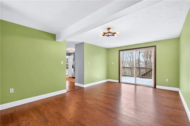 a view of an empty room with window and wooden floor