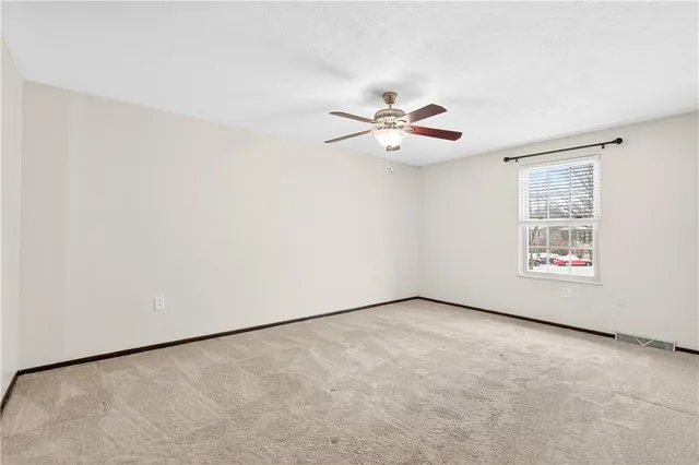 an empty room with windows and ceiling fan
