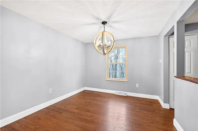 a view of empty room with wooden floor and window