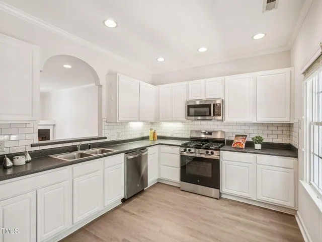 a kitchen with granite countertop white cabinets and stainless steel appliances