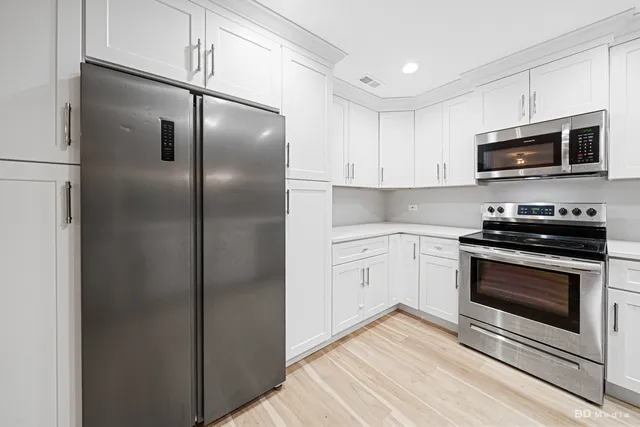 a kitchen with stainless steel appliances white cabinets and a stove top oven