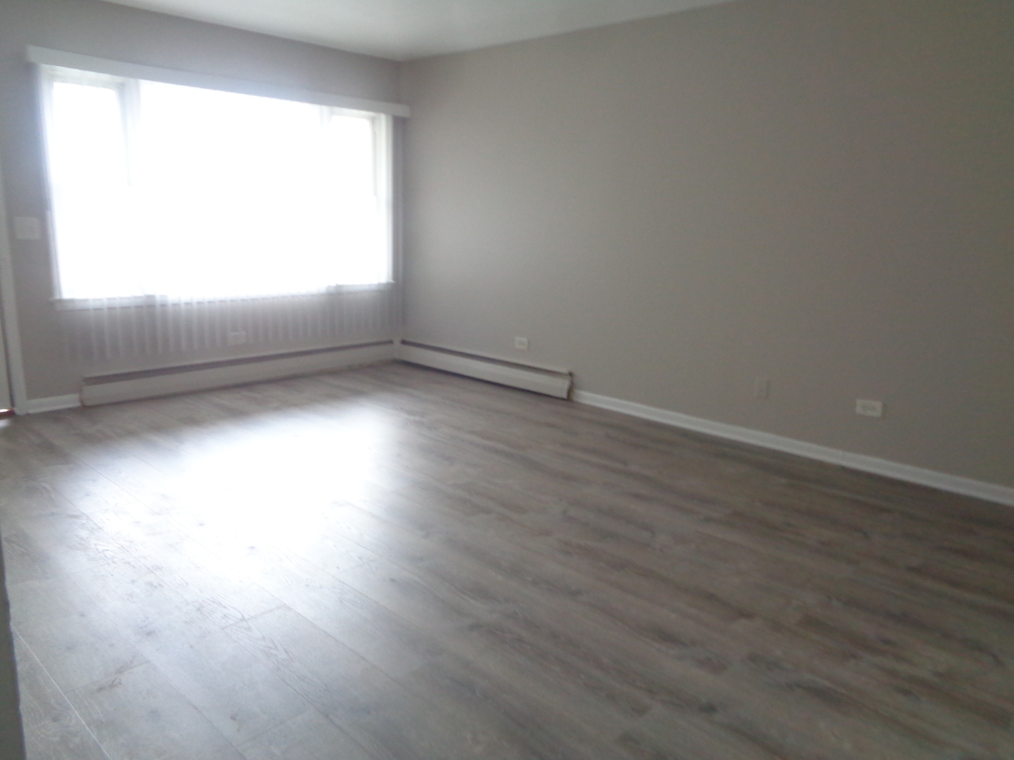 1340 North Main Street, Unit B11 Wheaton, IL 60187 - Photo 4 of 10 an empty room with wooden floor and windows