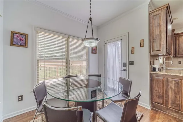 a kitchen with stainless steel appliances kitchen island granite countertop a stove top oven a sink a dining table and chairs with wooden floor