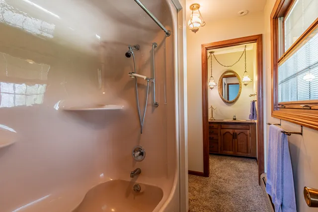 a bathroom with a tub a sink and mirror