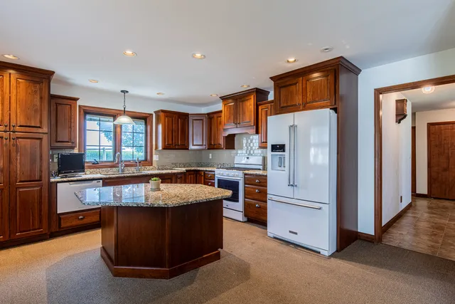 a kitchen with stainless steel appliances granite countertop a refrigerator a stove a sink and a refrigerator