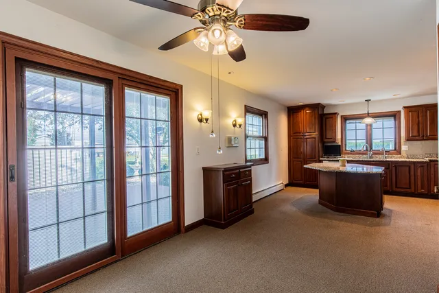 a large kitchen with stainless steel appliances granite countertop a refrigerator a sink dishwasher a stove and a dining table with wooden floor