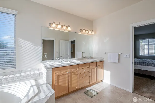 a spacious bathroom with a double vanity sink a mirror and a bathtub