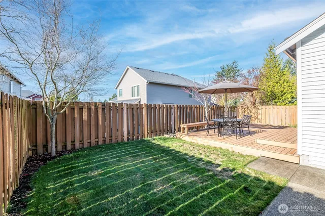 a view of a backyard with table and chairs under an umbrella with wooden fence