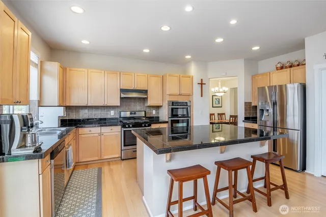 a kitchen with stainless steel appliances granite countertop a refrigerator a stove top oven a sink and dishwasher