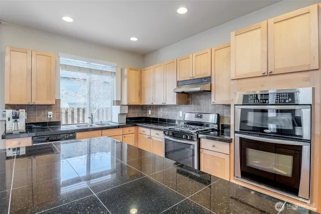 a kitchen with stainless steel appliances granite countertop a stove a sink and a microwave