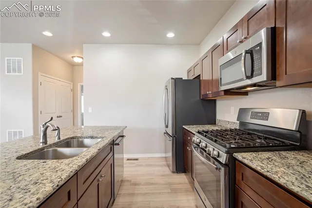 a kitchen with stainless steel appliances granite countertop a sink stove and refrigerator