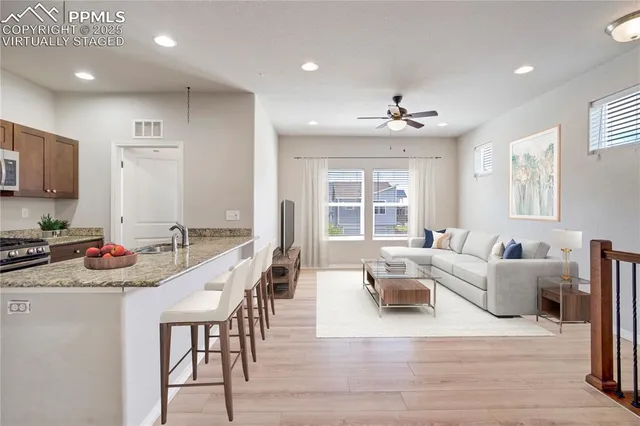 a kitchen with stainless steel appliances granite countertop a sink dishwasher a dining table and chairs with wooden floor