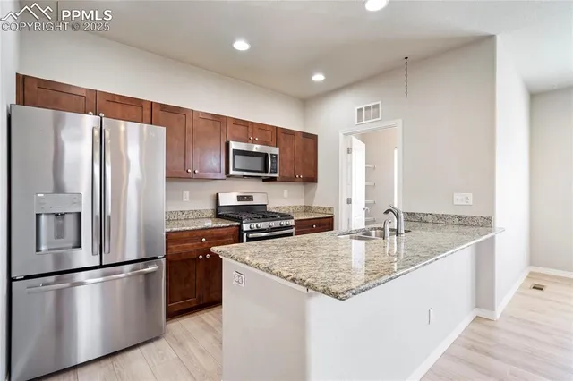 a kitchen with stainless steel appliances granite countertop a refrigerator a stove a sink a microwave and cabinets