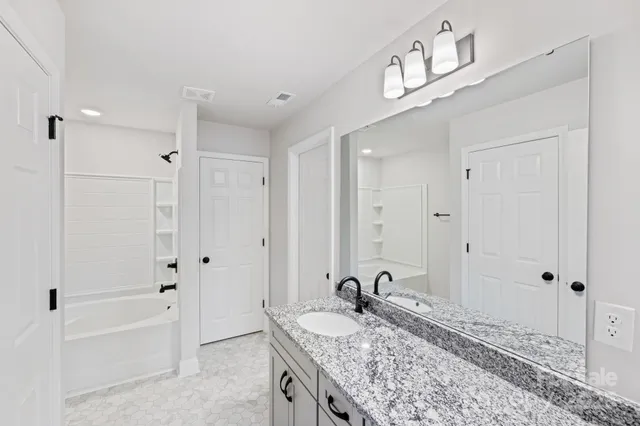 a bathroom with a granite countertop tub sink and mirror