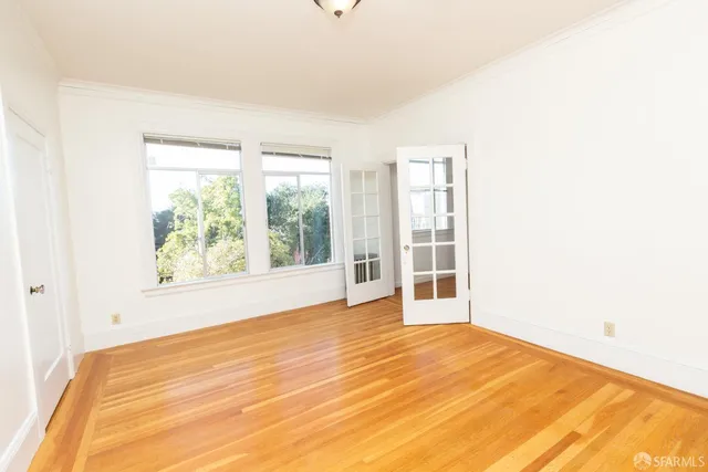 a view of an empty room with wooden floor and a window