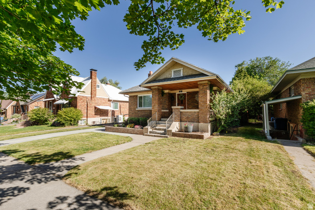 227 West 200 North Logan, UT 84321 - Photo 5 of 44 Brick bungalow featuring a covered front porch with substantial columns, a pitched roof, and a visible address number