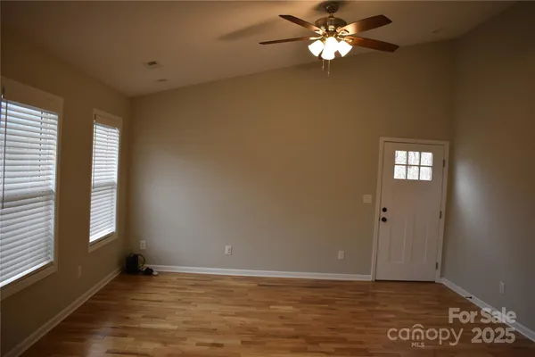 a view of an empty room with window and chandelier fan