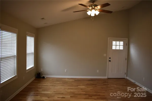a view of an empty room with window and chandelier fan