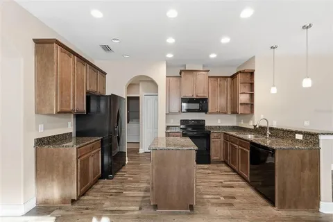 a kitchen with stainless steel appliances granite countertop a refrigerator a stove a sink and a microwave