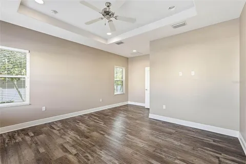 an empty room with wooden floor fan and windows