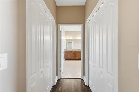 a view of a hallway with wooden floor and a bathroom
