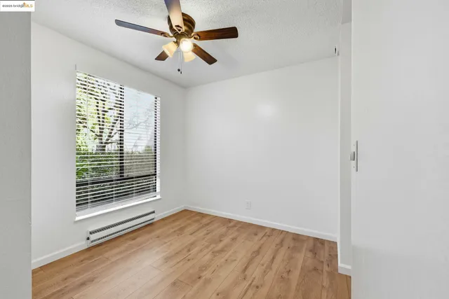 an empty room with wooden floor fan and windows