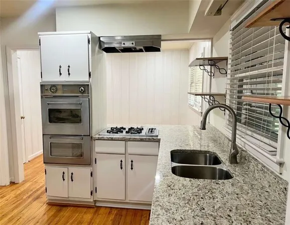 a kitchen with granite countertop a sink cabinets and stainless steel appliances
