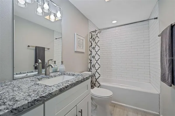 a bathroom with a granite countertop sink a toilet and shower