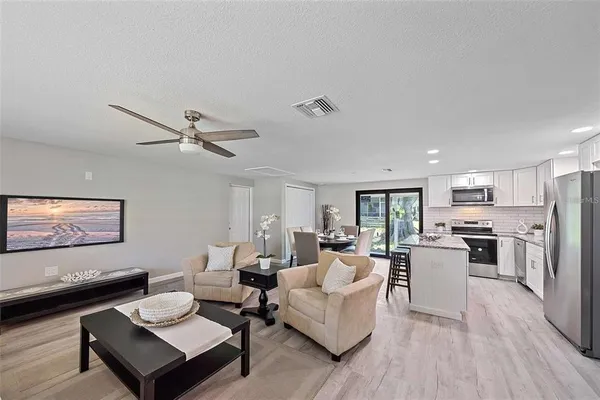 a living room with furniture kitchen view and a window