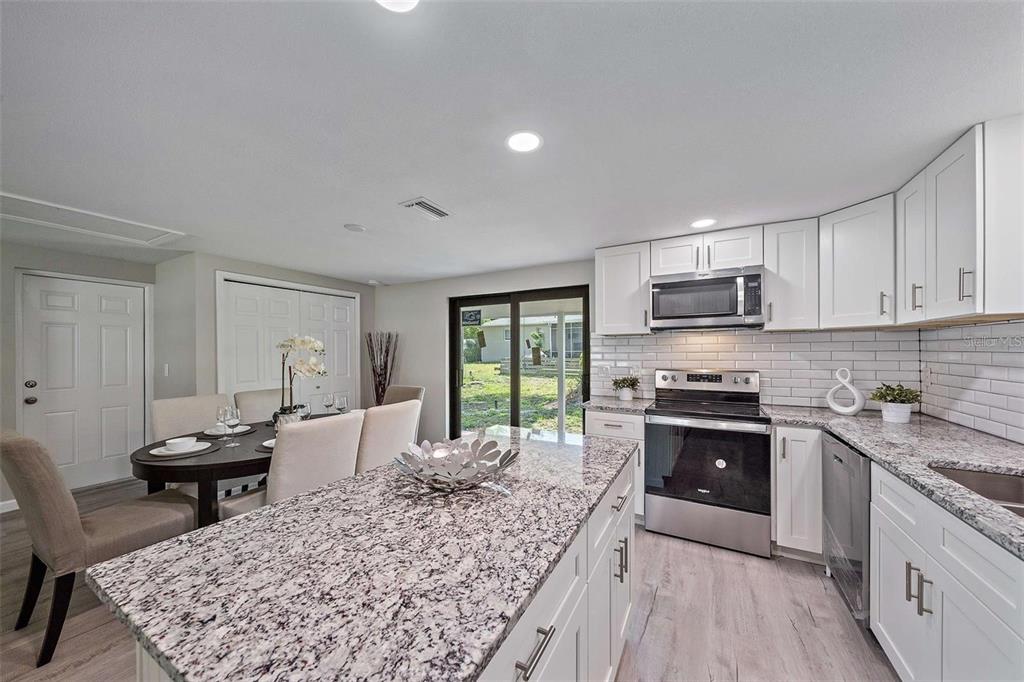 105 Clemson Road Venice, FL 34293 - Photo 5 of 15 a large kitchen with kitchen island granite countertop lots of counter top space a sink appliances and cabinets