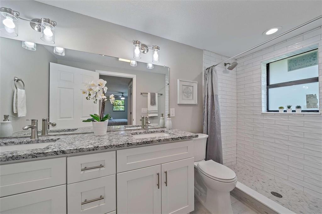 105 Clemson Road Venice, FL 34293 - Photo 10 of 15 a bathroom with a granite countertop sink a toilet and a mirror