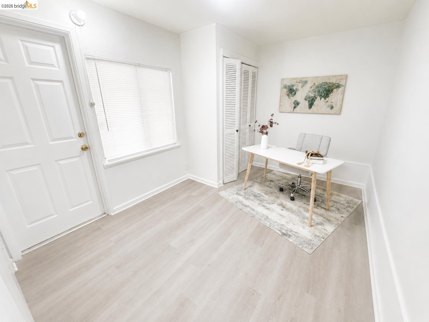 810 Pierce Street Albany, CA 94706 - Photo 14 of 25 Bright interior space featuring light wood-finish flooring, a panel-style door with brass hardware, a window with horizontal blinds, and louvered bi-fold closet doors