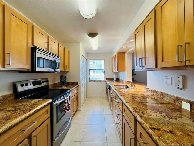 a kitchen with granite countertop sink cabinets and stove