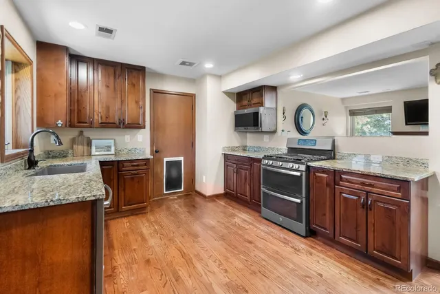 a kitchen with stainless steel appliances granite countertop wooden cabinets a stove top oven a sink and dishwasher