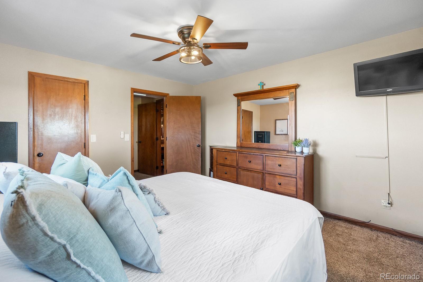 3163 Windstream Lane Elizabeth, CO 80107 - Photo 15 of 48 a bedroom with a large bed a flat tv screen and dresser