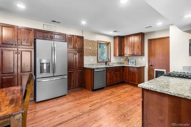 a kitchen with stainless steel appliances granite countertop a refrigerator a sink a stove a washer dryer and a refrigerator