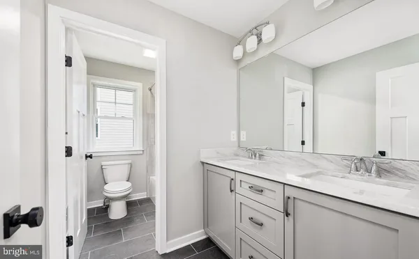 a bathroom with a granite countertop sink a toilet and a mirror