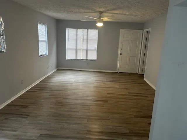 an empty room with wooden floor and windows