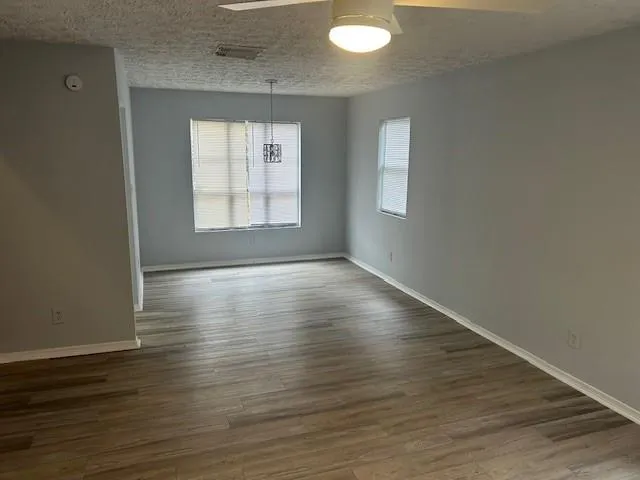 an empty room with wooden floor and windows
