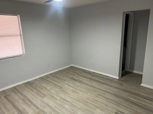 an empty room with wooden floor and windows